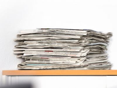 Das Bild zeigt einen Zeitungsstapel. Der Artikel geht der Frage nach, ob der Trend des Clickbaiting auch im Printjournalismus zu schlechten Überschriften führt.