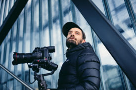 Portraitbild von Mann mit Kamera auf Stativ